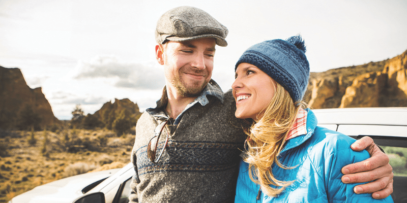 A man and a woman standing next to a car