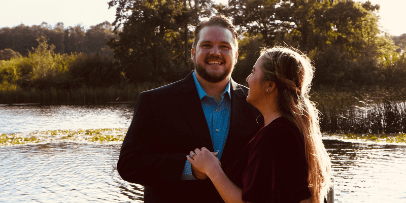 A man and woman standing next to each other in front of a body of water