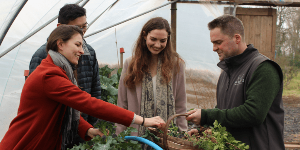 A group of people standing around a plant in a greenhouse