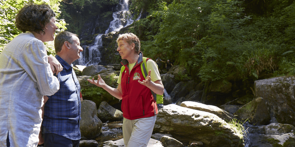 Three people standing in front of a waterfall