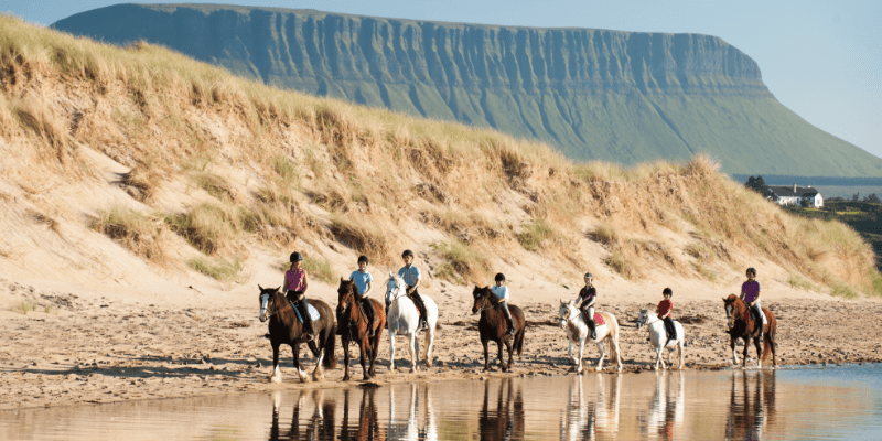 People riding horses with cliffs in the background