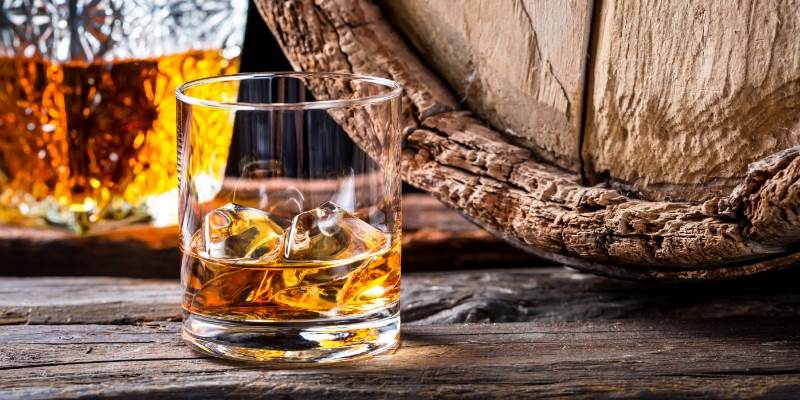 A glass of whiskey sitting on top of a wooden table
