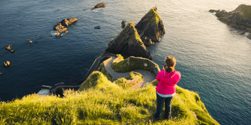 A woman standing on top of a lush green hillside