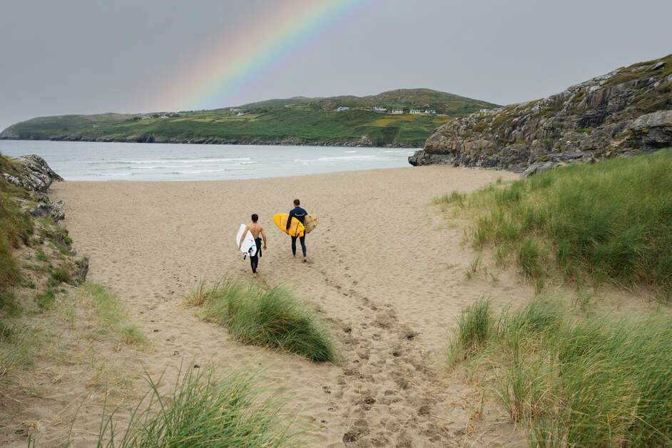A couple of people with surfboards walking on a beach