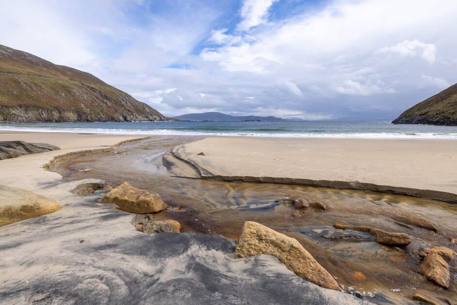 A sandy beach with rocks and a body of water