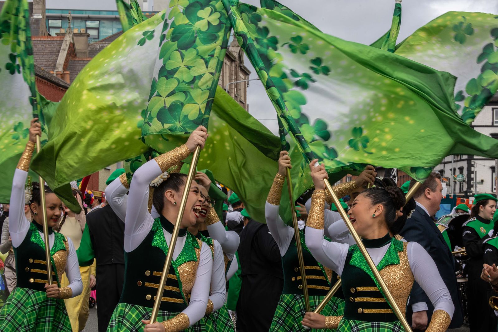 Two people in traditional dress, waving flags in a St. Patrick's Day parade in Dublin, Ireland.
