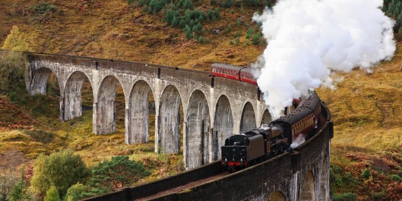 A train traveling over a bridge with steam pouring out of it