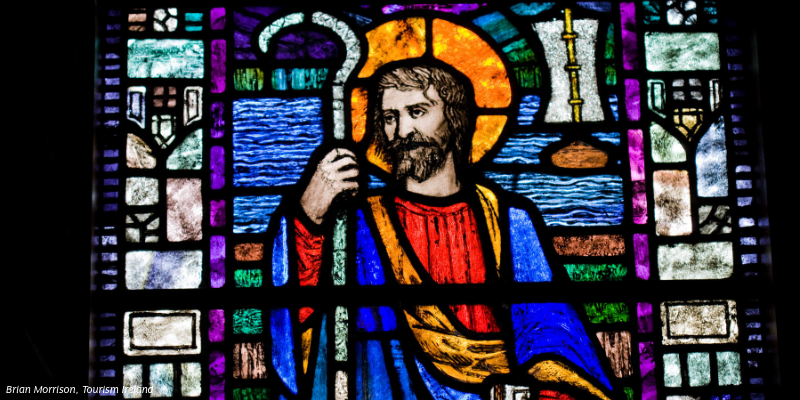 A stained glass window with St. Patrick holding a cross