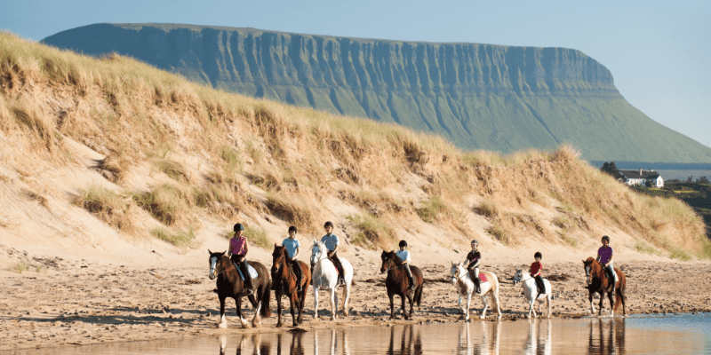People riding horses on a beach