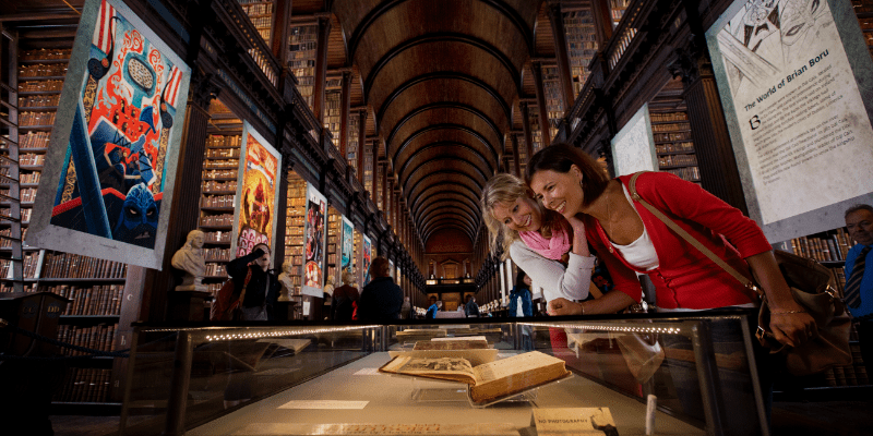 Two women looking at a book in a library