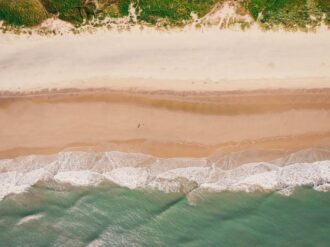 An aerial view of a sandy beach and ocean