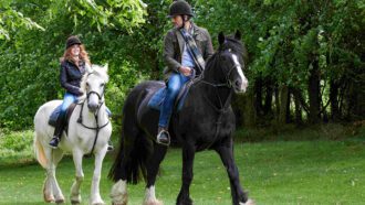 Man riding a black horse and woman riding a white horse