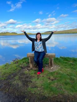 Woman sitting on stone bench in front of lake near Belfast in Ireland