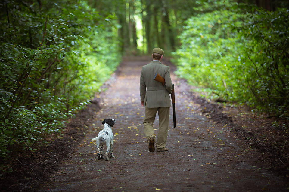 A man walking down a dirt road with a dog