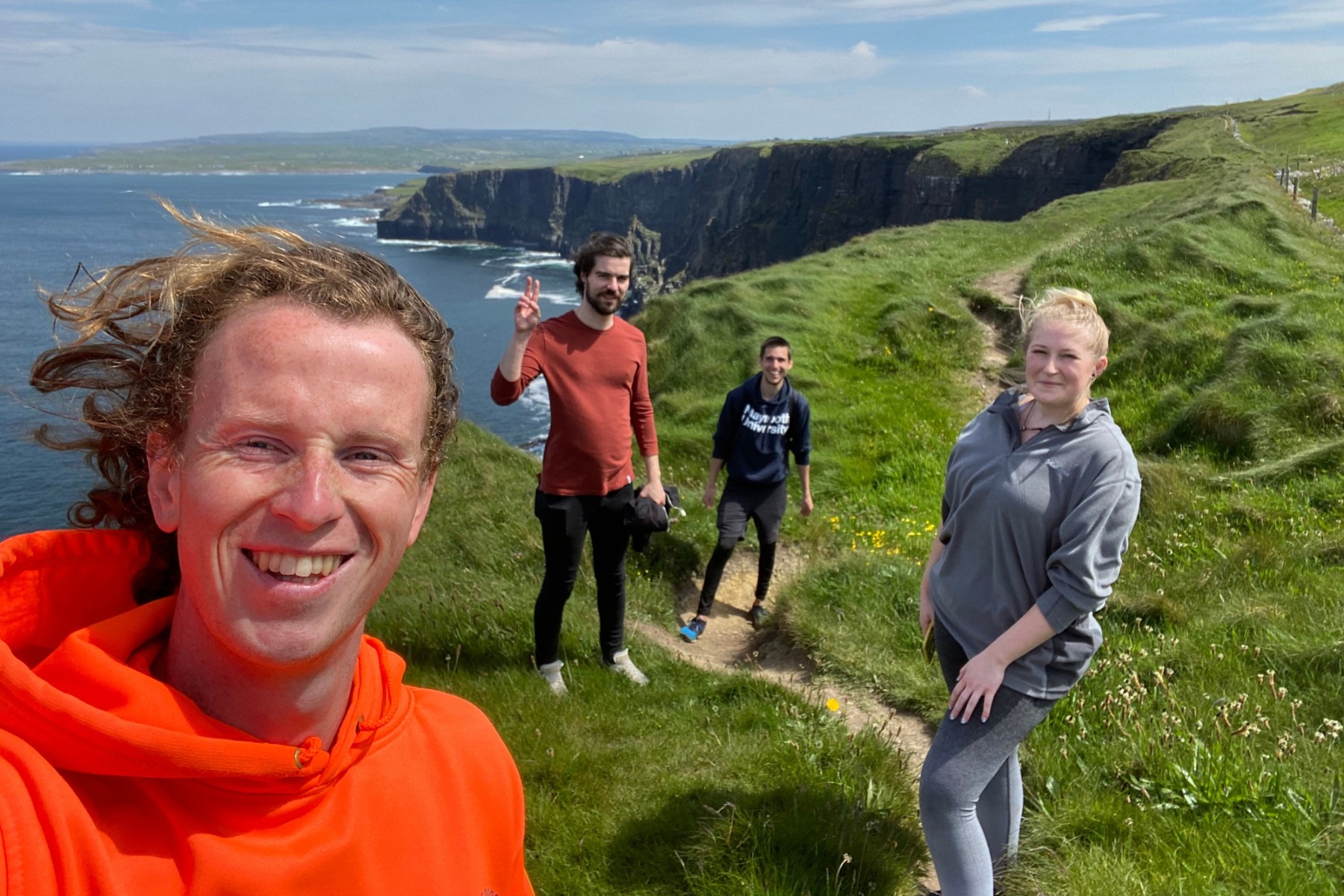 Happy people on a hike on the top of cliffs on a sunny day