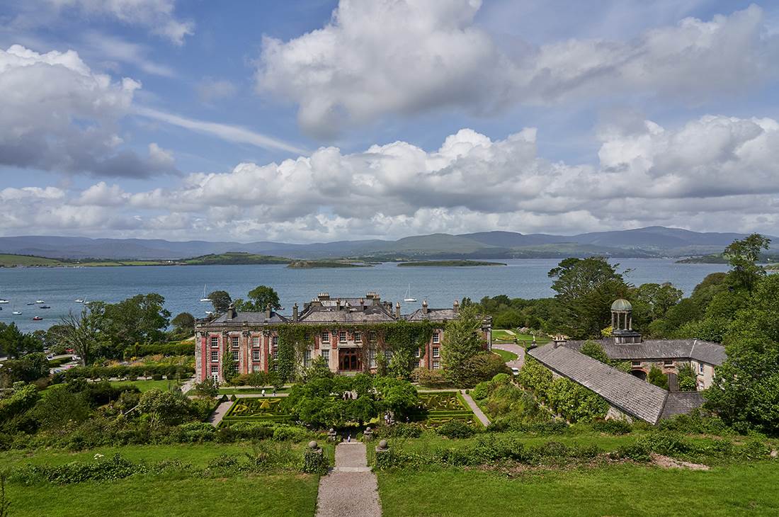 A large house surrounded by greenery and water