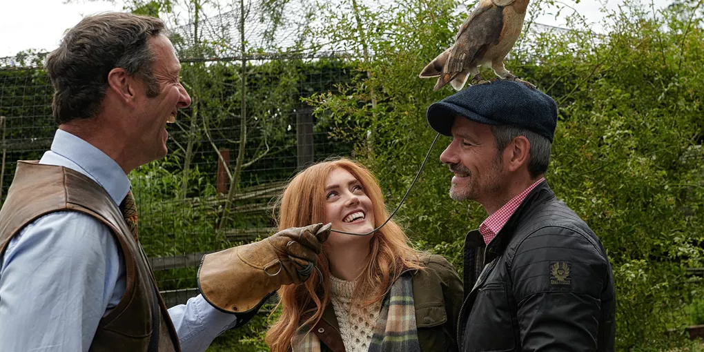 Two men and a woman enjoying falconry activity in Dromoland Castle