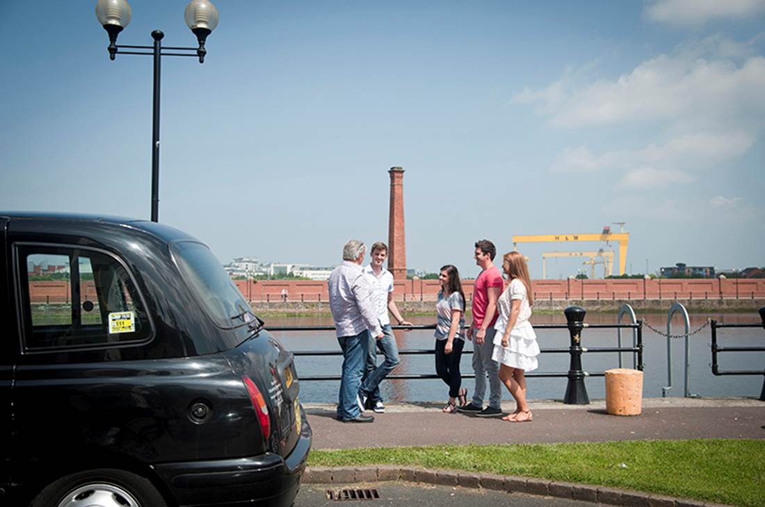People on bridge with black cab on front