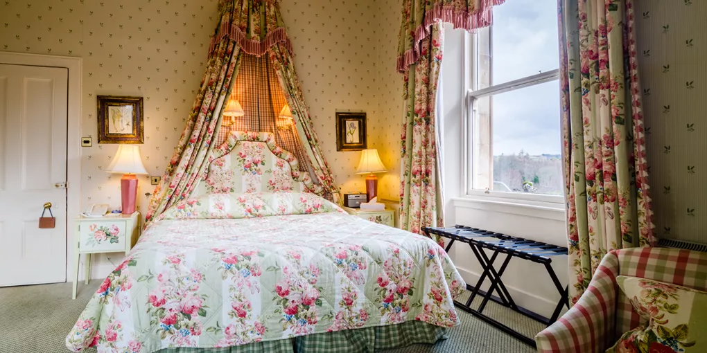A bed sitting in a bedroom next to a window in Inverlochy Castle in Scotland's Highlands