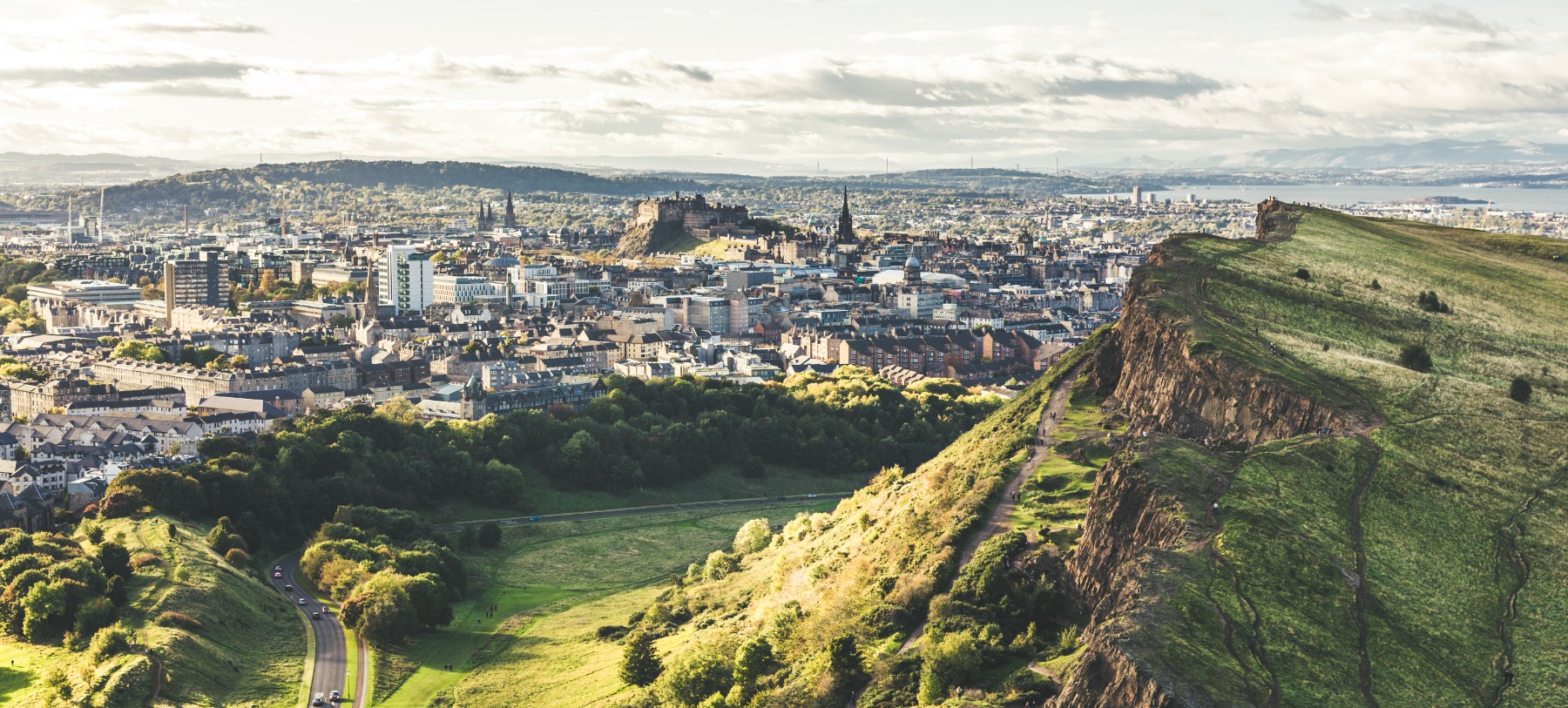 An aerial view of Edinburgh Scotland looking out from Arthur's Seat, a large grass covered hill.
