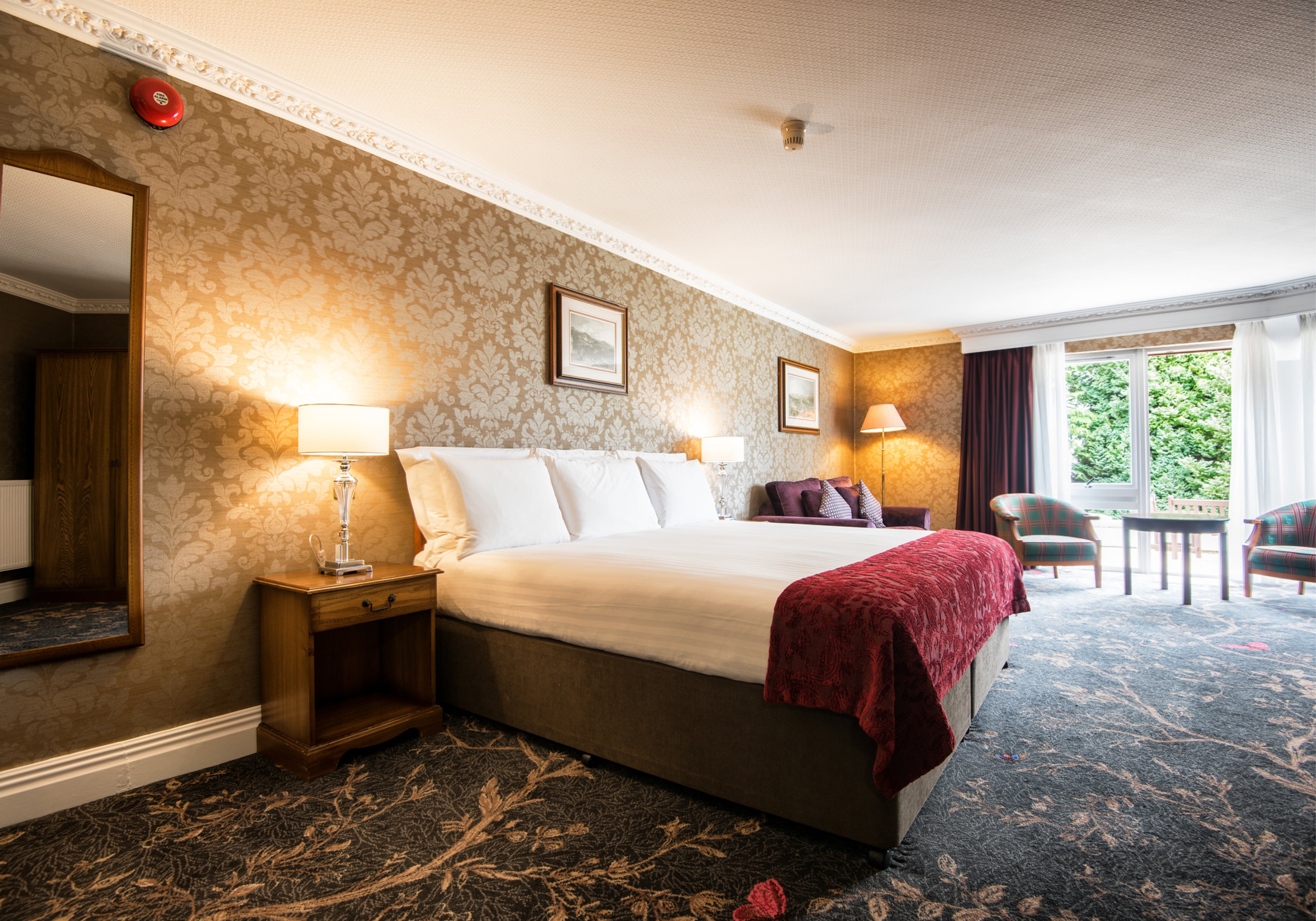 Classic studio with a large bed and floral wallpaper at Kingsmills Hotel, Inverness 