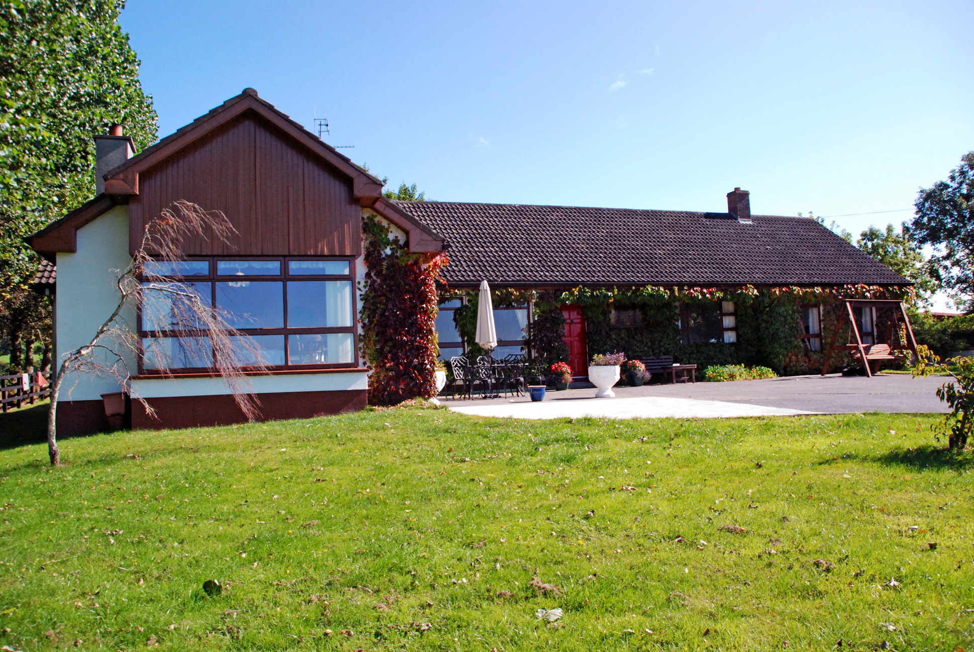 Bungalow B&B exterior with a large lawn in front of it 