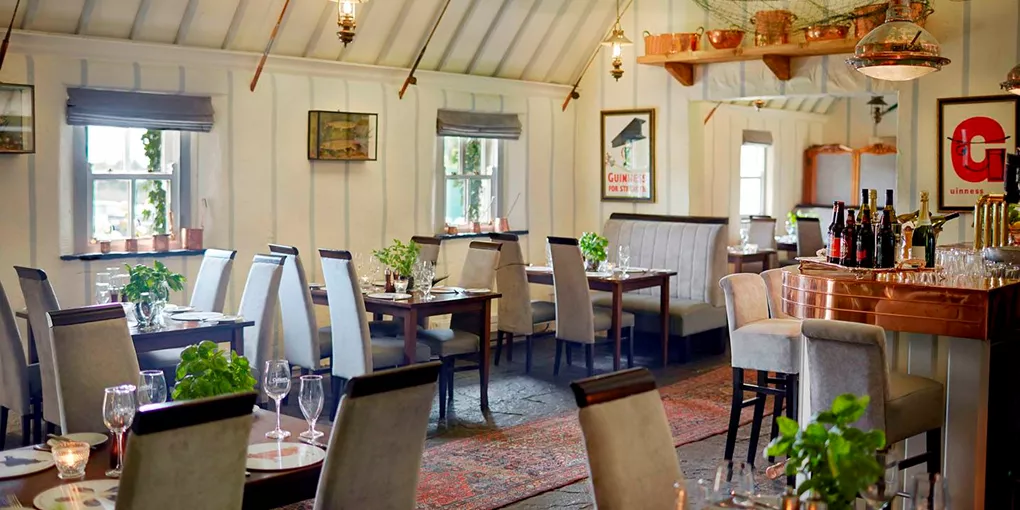A restaurant with tables, chairs, and a bar in Ashford Castle