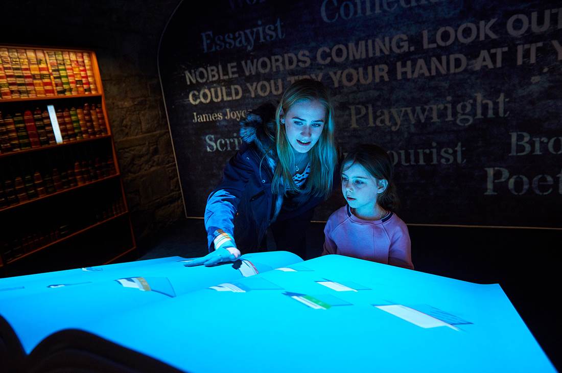 A woman and a little girl standing in front of a book