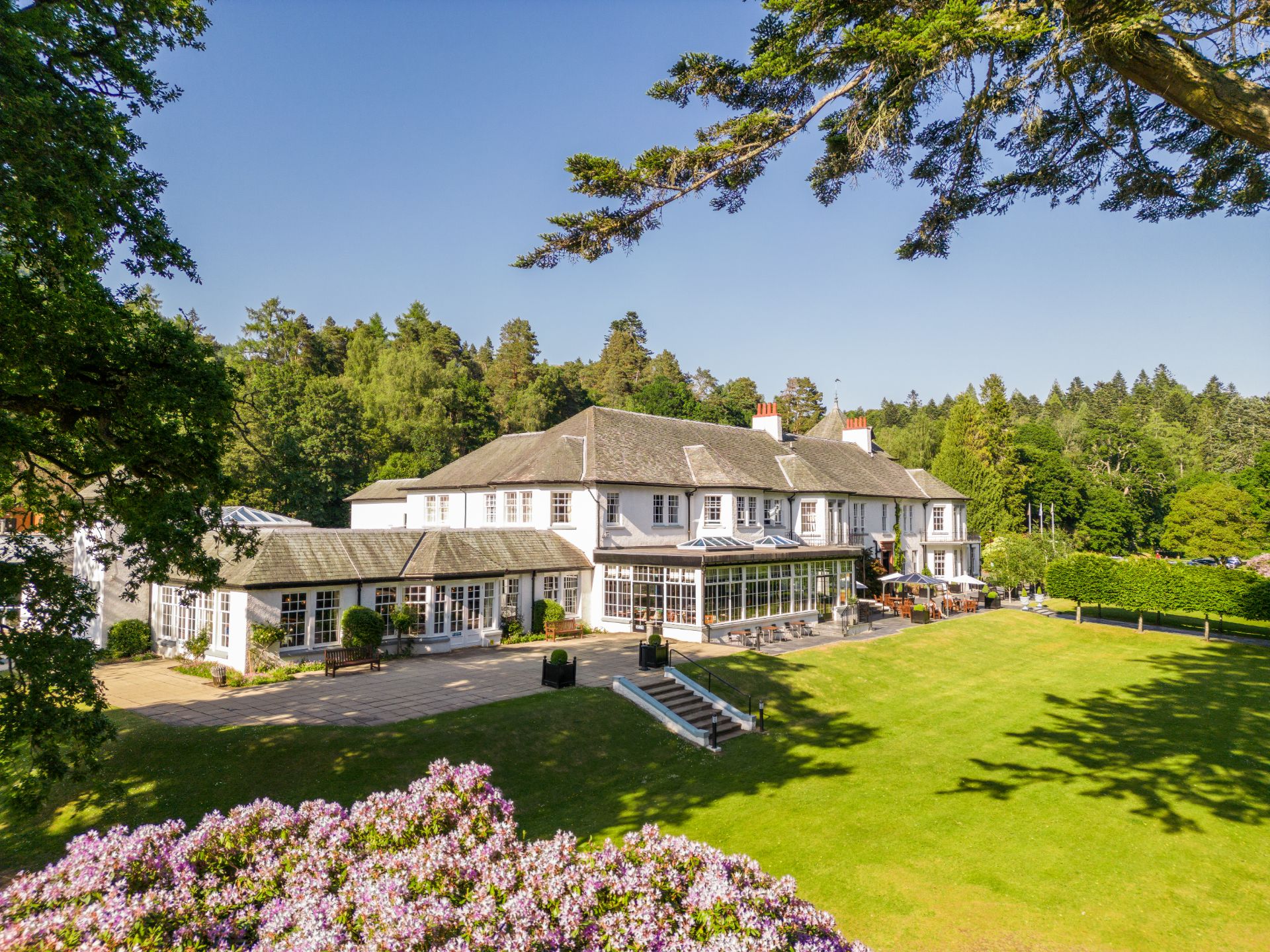 A large white house surrounded by trees and flowers