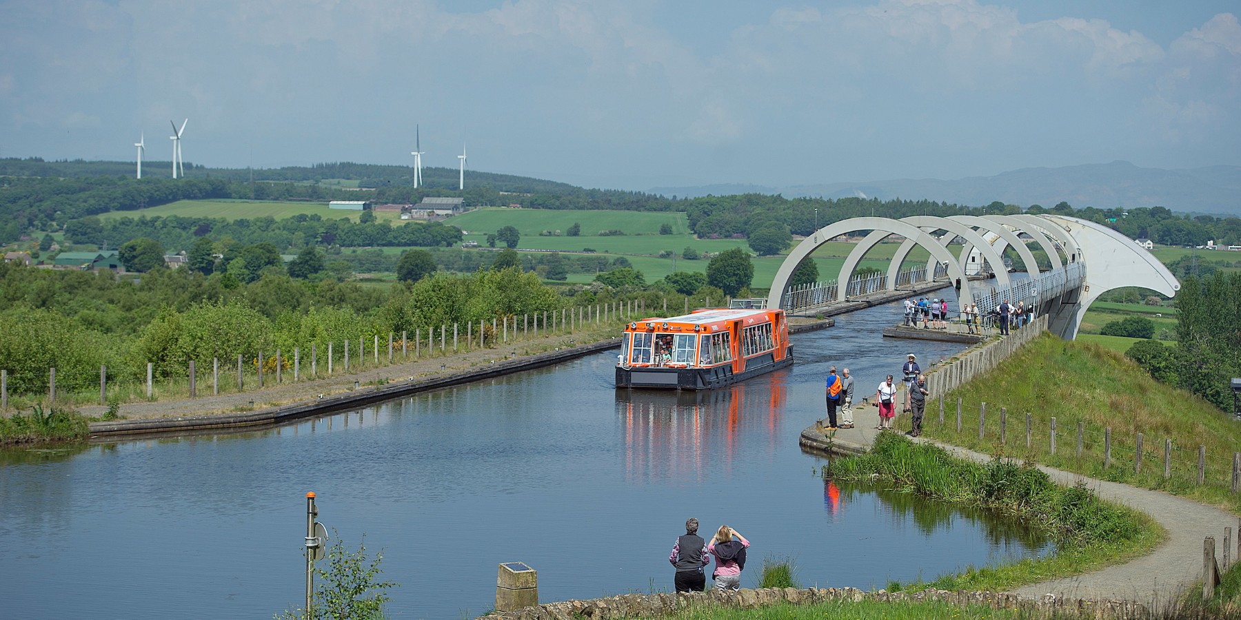 A boat traveling down a river next to a bridge
