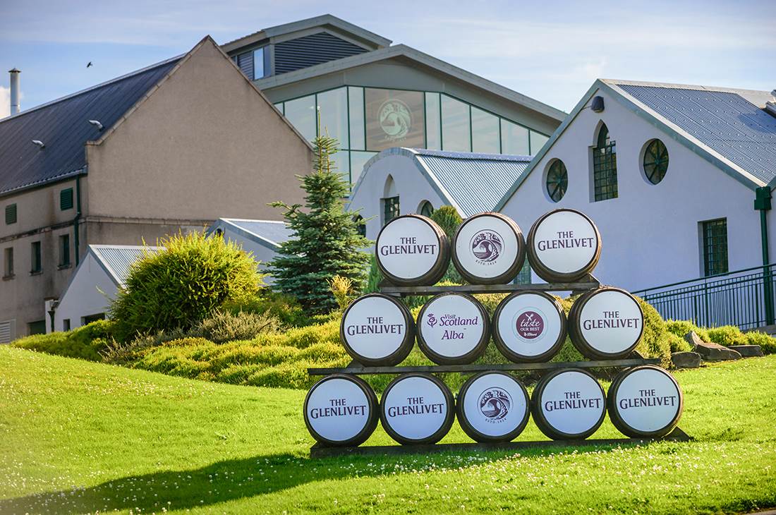 Rows of barrels stacked on top of each other in the background of buildings