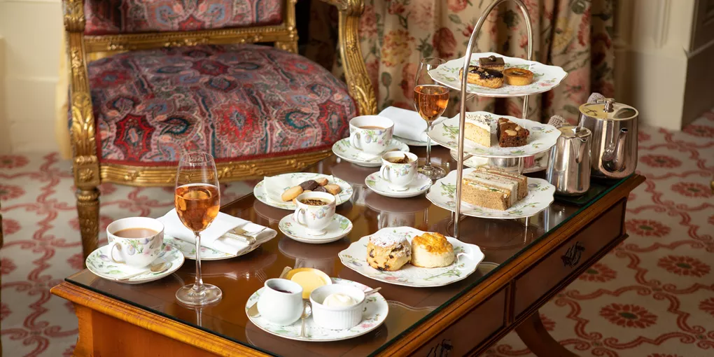 A wooden table topped with plates of food and cups of tea