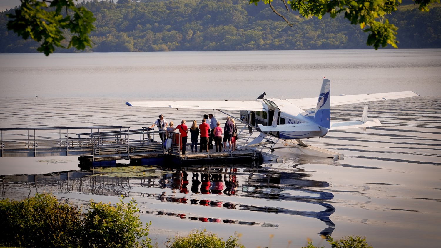 A group of people standing on a dock next to an airplane
