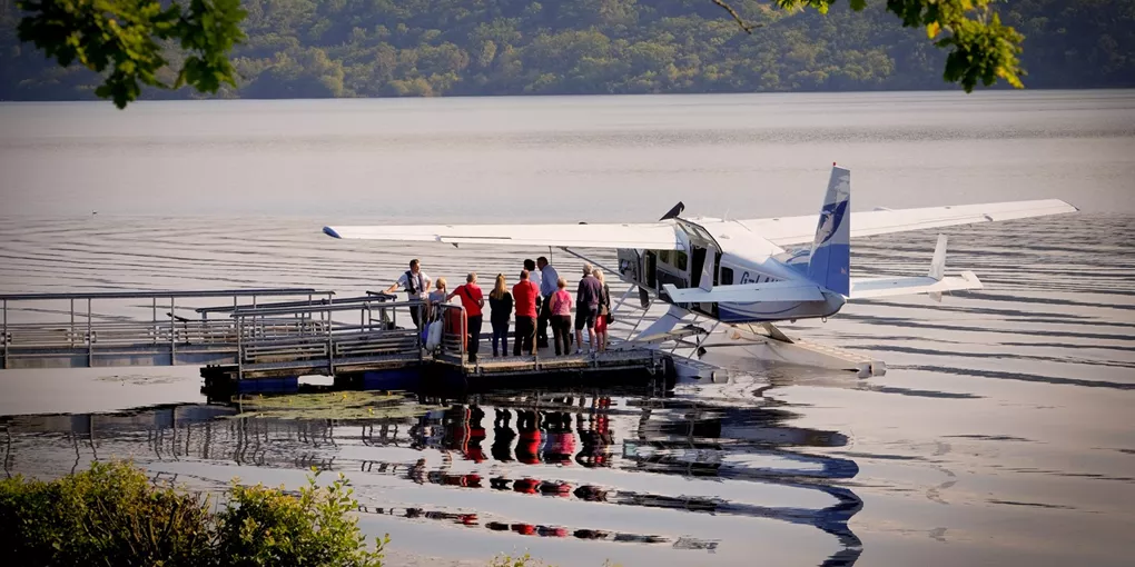 A group of people standing on a dock next to an airplane