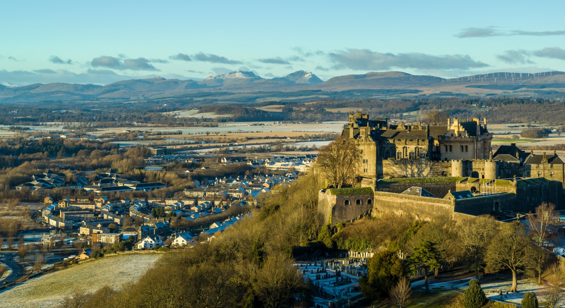 A castle overlooking a town with mountains in the background