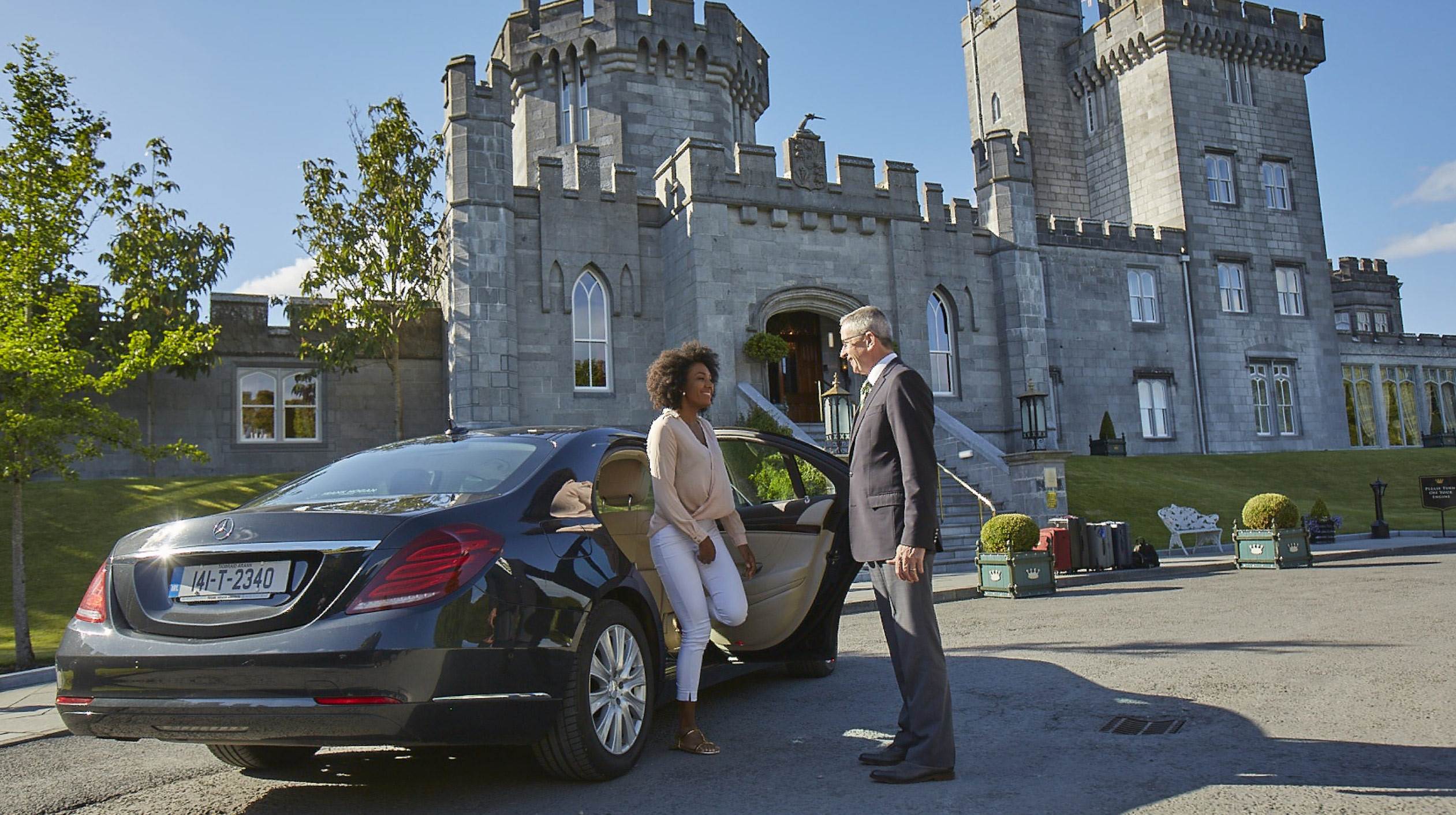 A man and woman standing next to a car in front of a castle