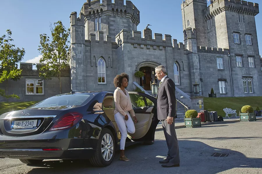 A man and woman standing next to a car in front of a castle