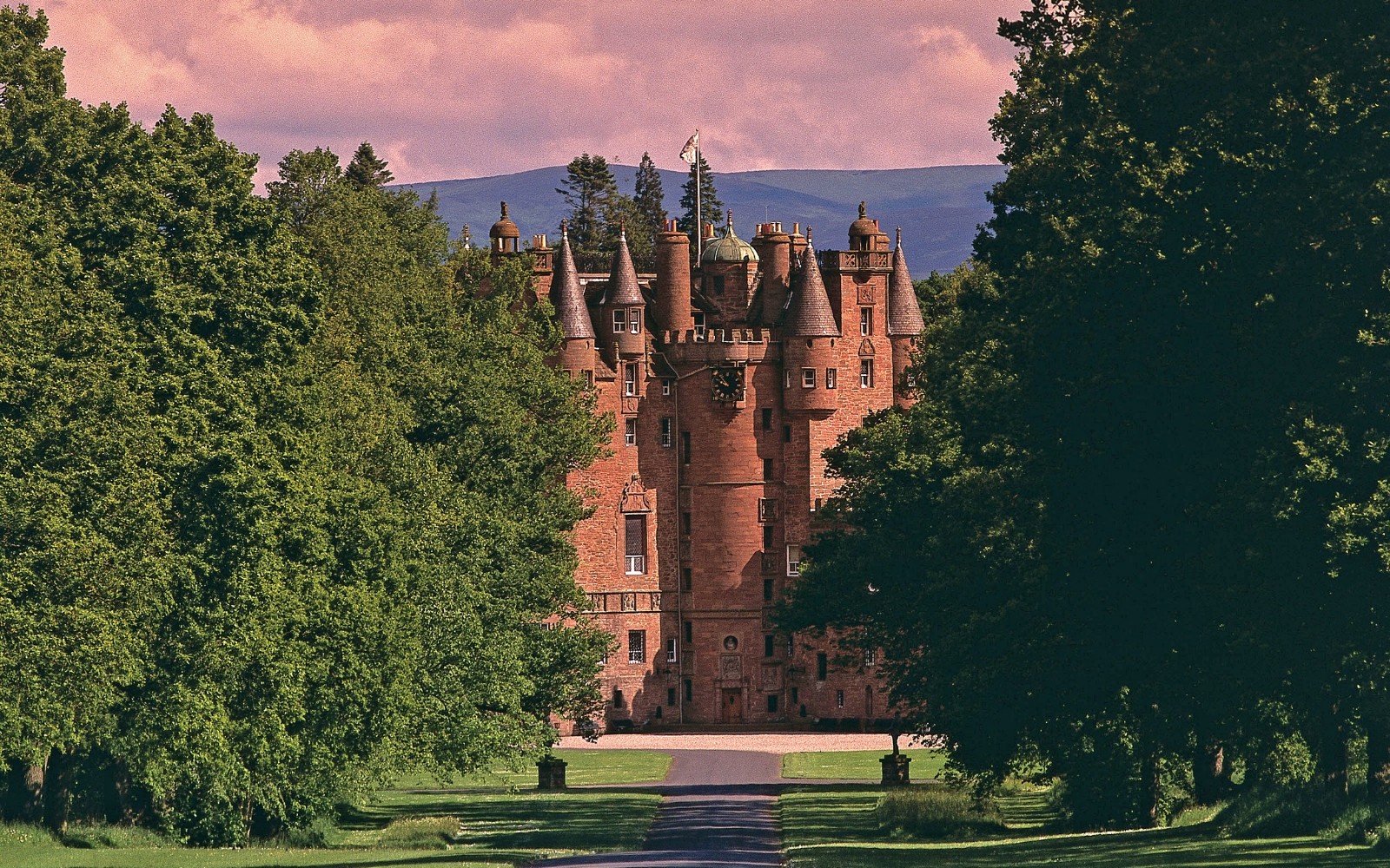 A large brick building with a clock tower on top of it among the trees
