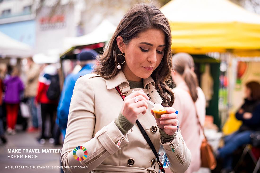 A woman in a trench coat eating a dessert