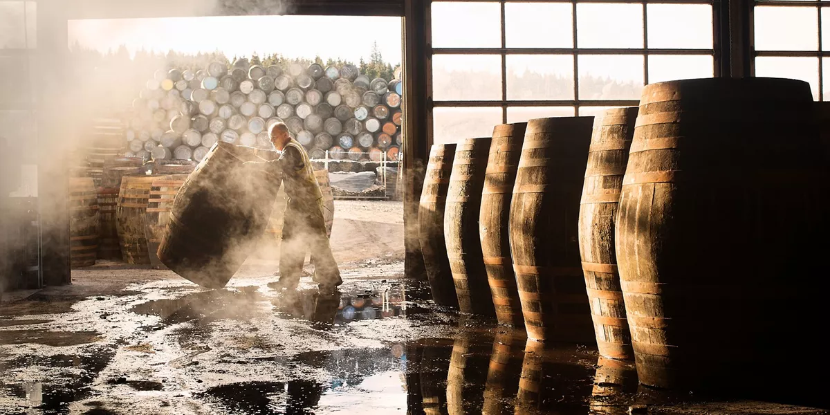 Row of whiskey barrels with man pushing one in the entrance