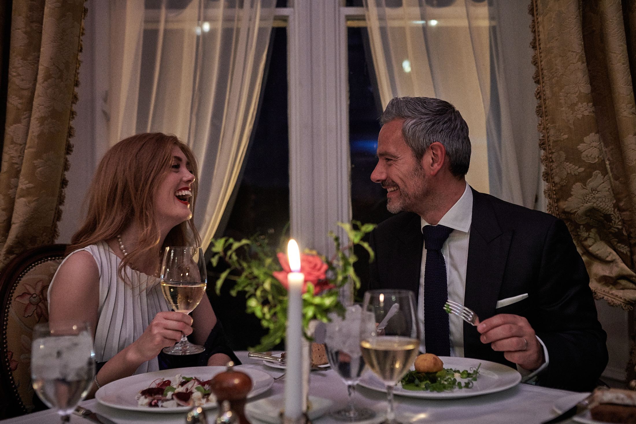 Couple sitting by the table laughing and talking during elegant dinner in Dromoland Castle