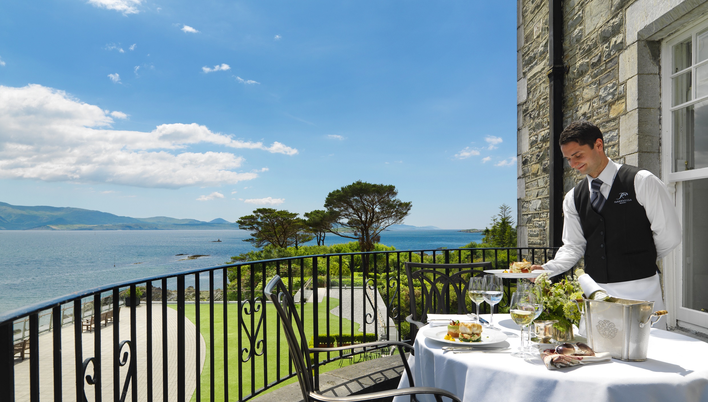 A waiter serving dinner on balcony in Parknasilla Resort & Spa in Sneem, Ireland