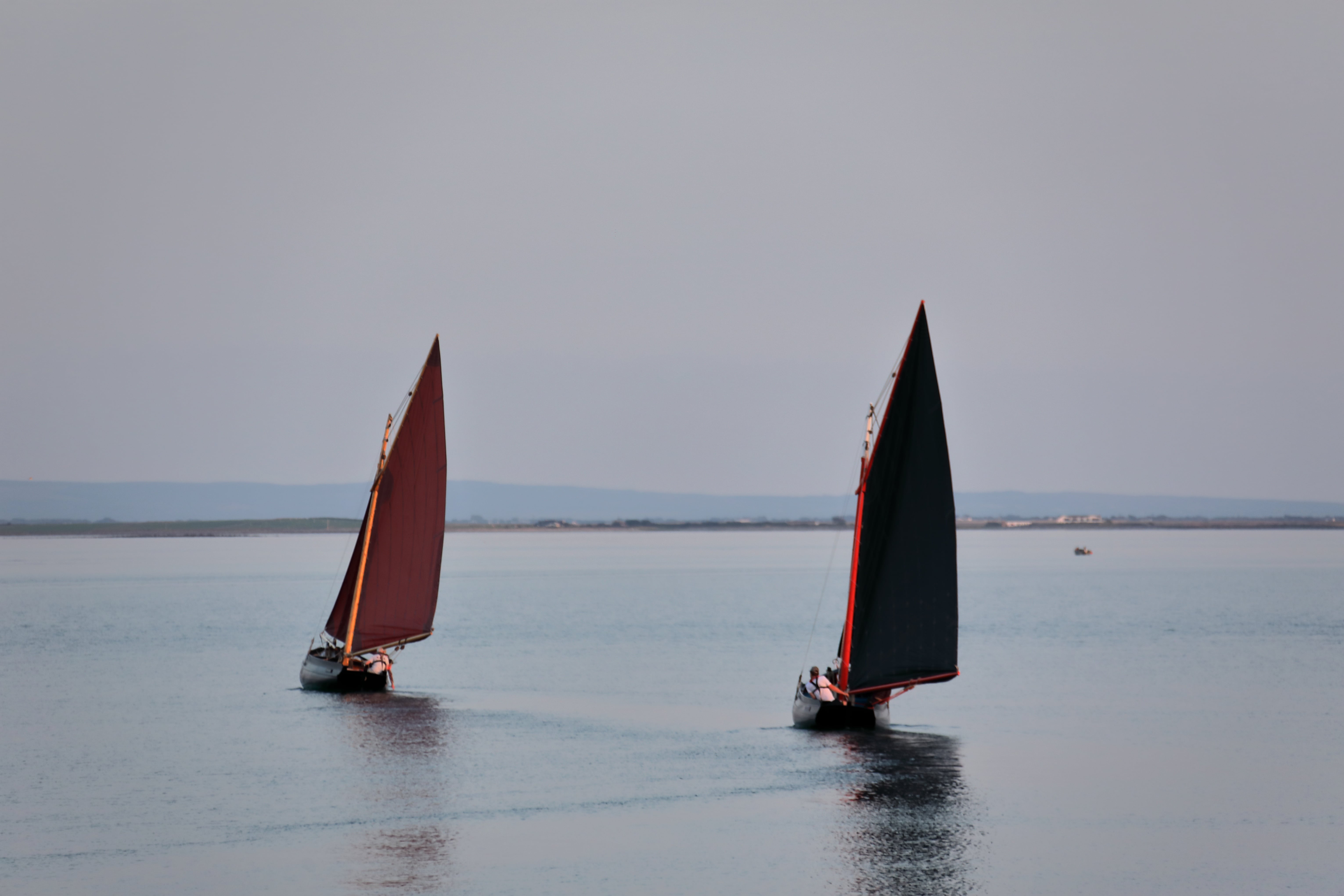 A couple of small boats floating on top of a large body of water