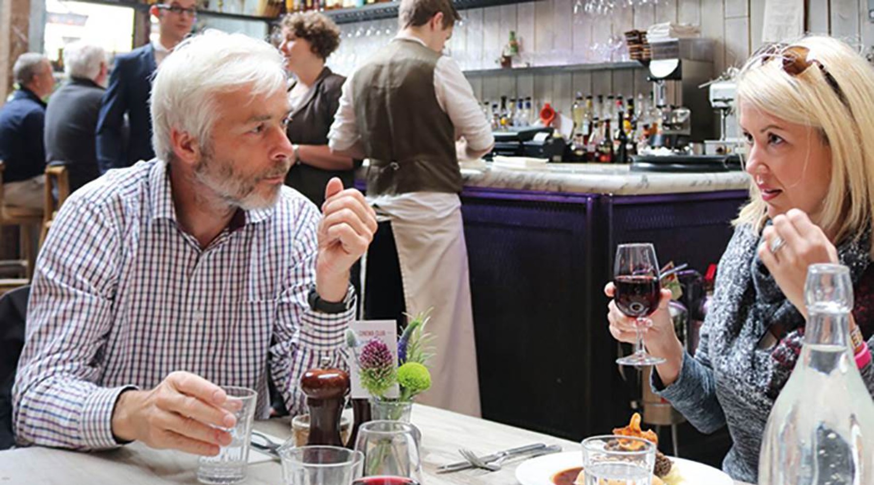 A man and a woman have dinner and drink wine in a restaurant