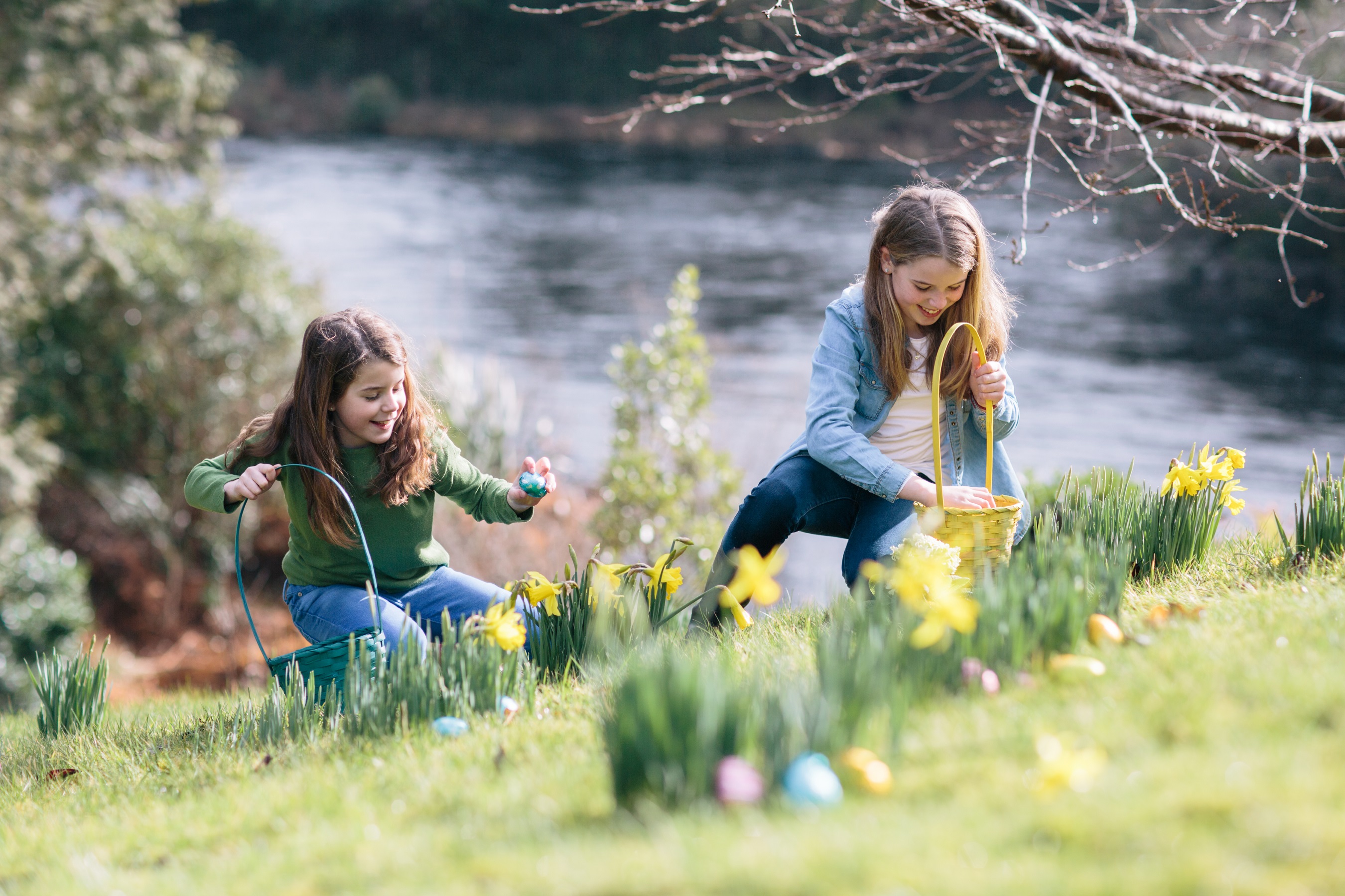Two young girls picking Easter eggs in a field