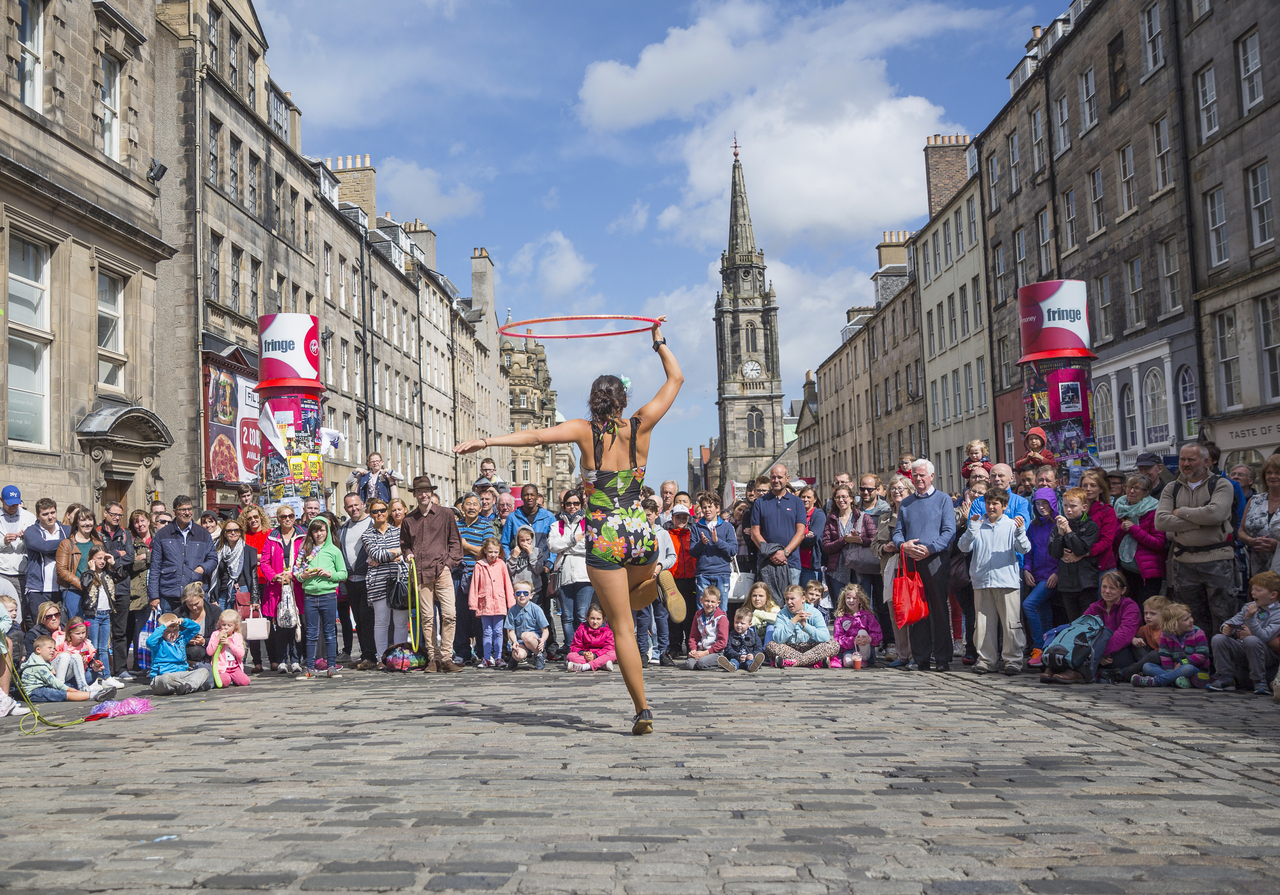 A woman with a hula hoop performing in front of a crowd of people at Edinburgh Fringe Festival