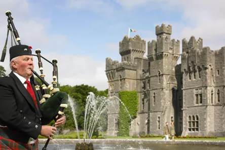 A man playing bagpipes in front of a castle