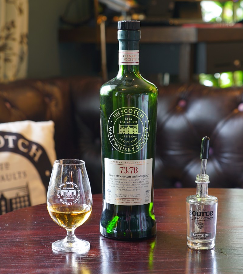 A bottle of The Scotch whisky and a glass on the wooden table