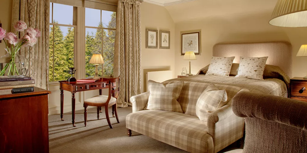 A bedroom with a bed, chair, desk and window