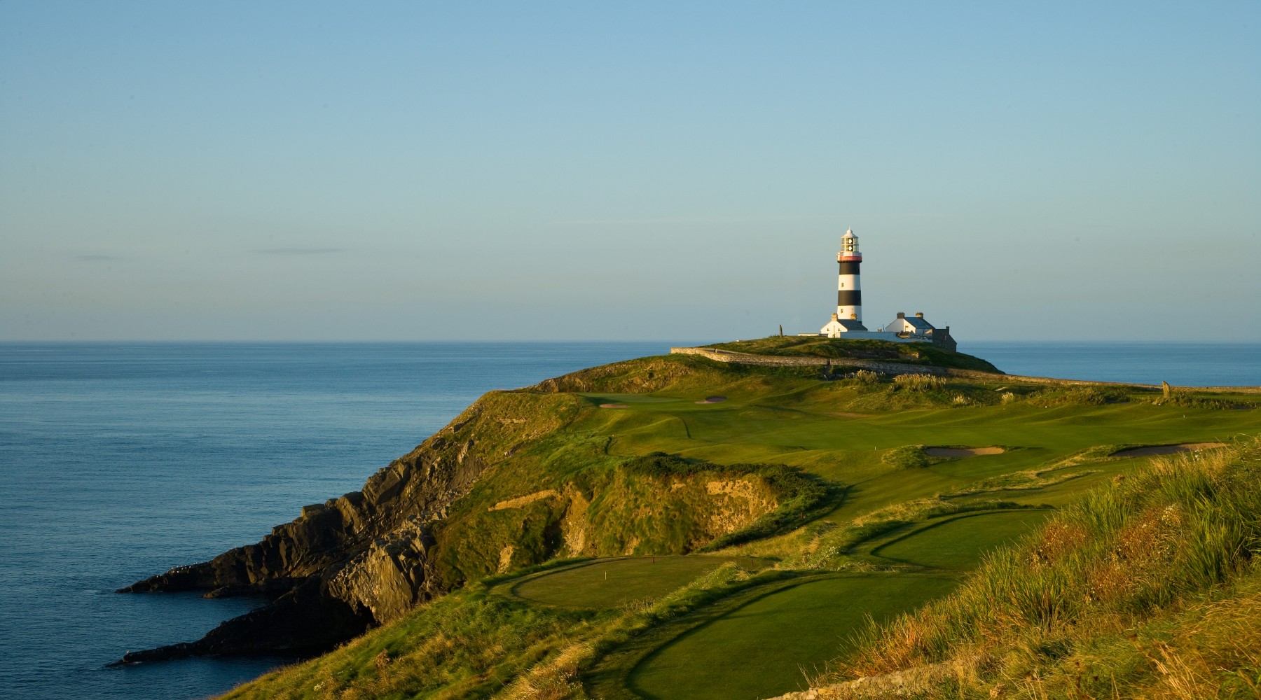 A lighthouse on top of a hill near the ocean